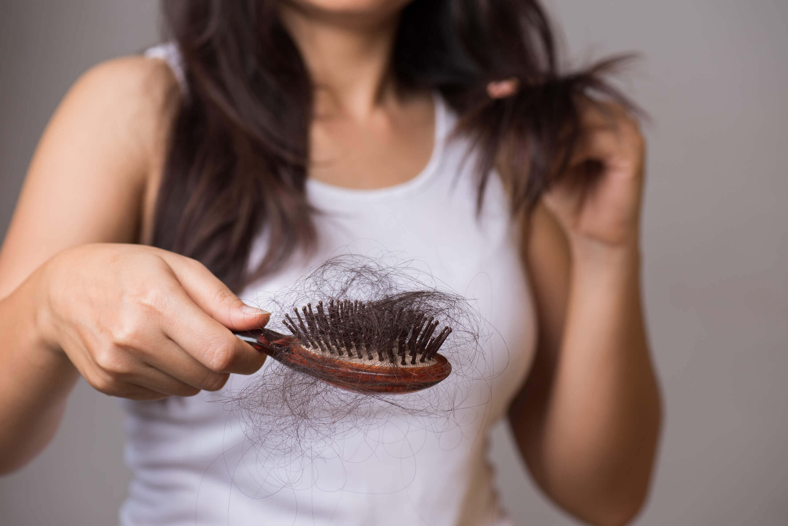 Frau hält Bürste mit vielen Haaren darin