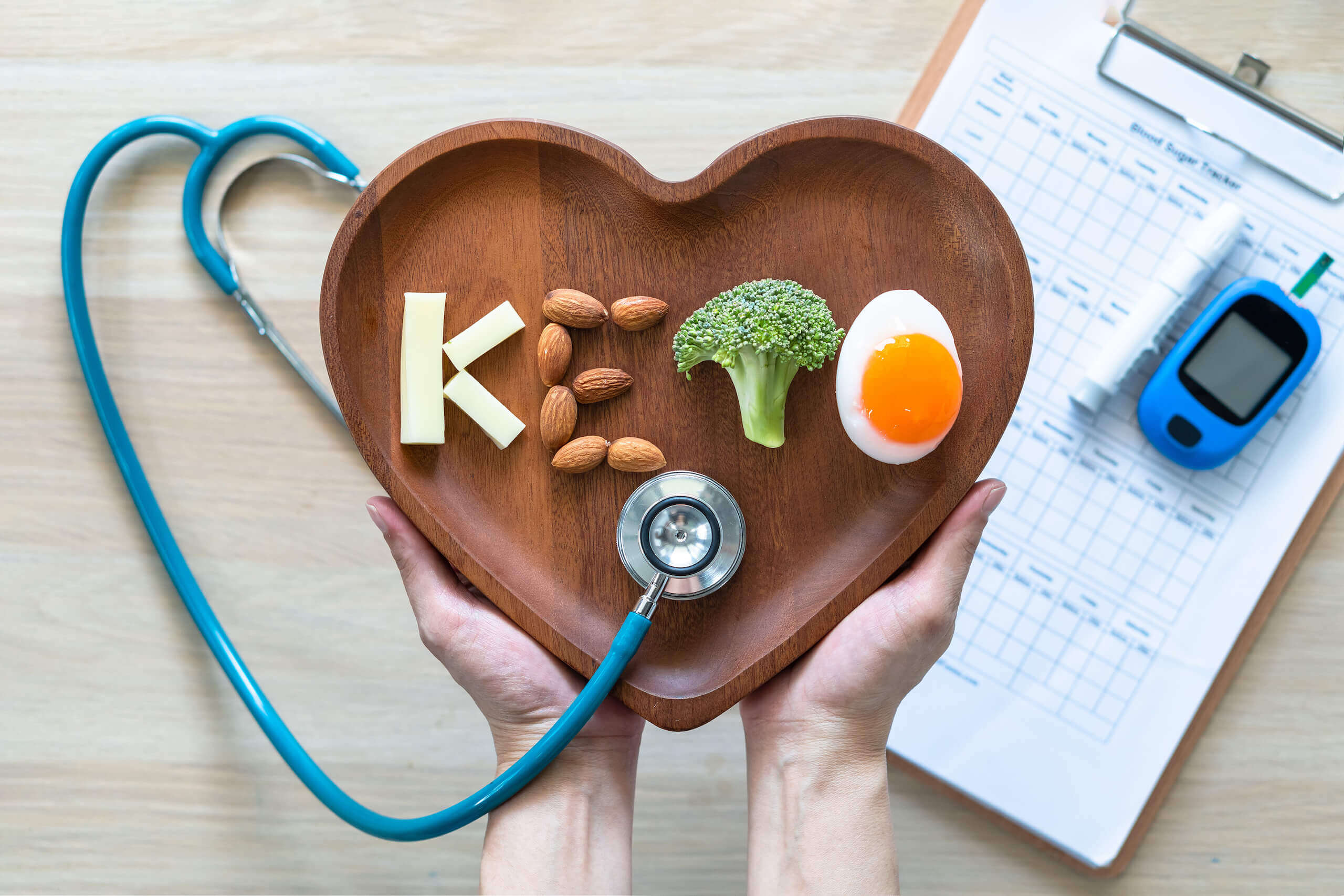 med4you_ketose_00002 Holzteller in Herzform mit "Keto"-Schriftzug aus Lebensmitteln gelegt